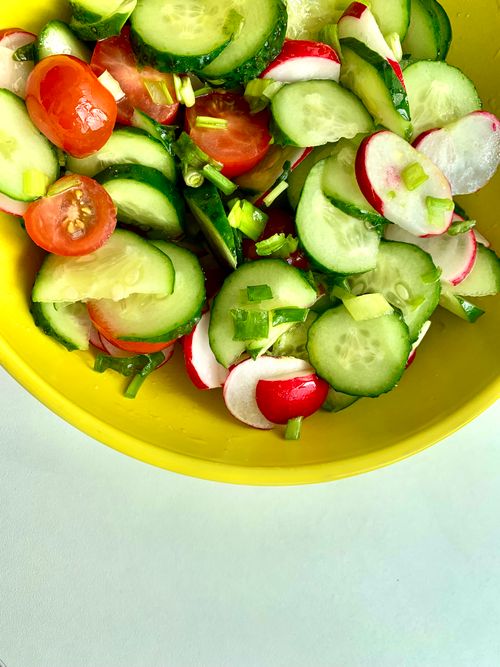 Free Bright and colorful vegetable salad with cucumbers, tomatoes, and radishes in a yellow bowl. Stock Photo