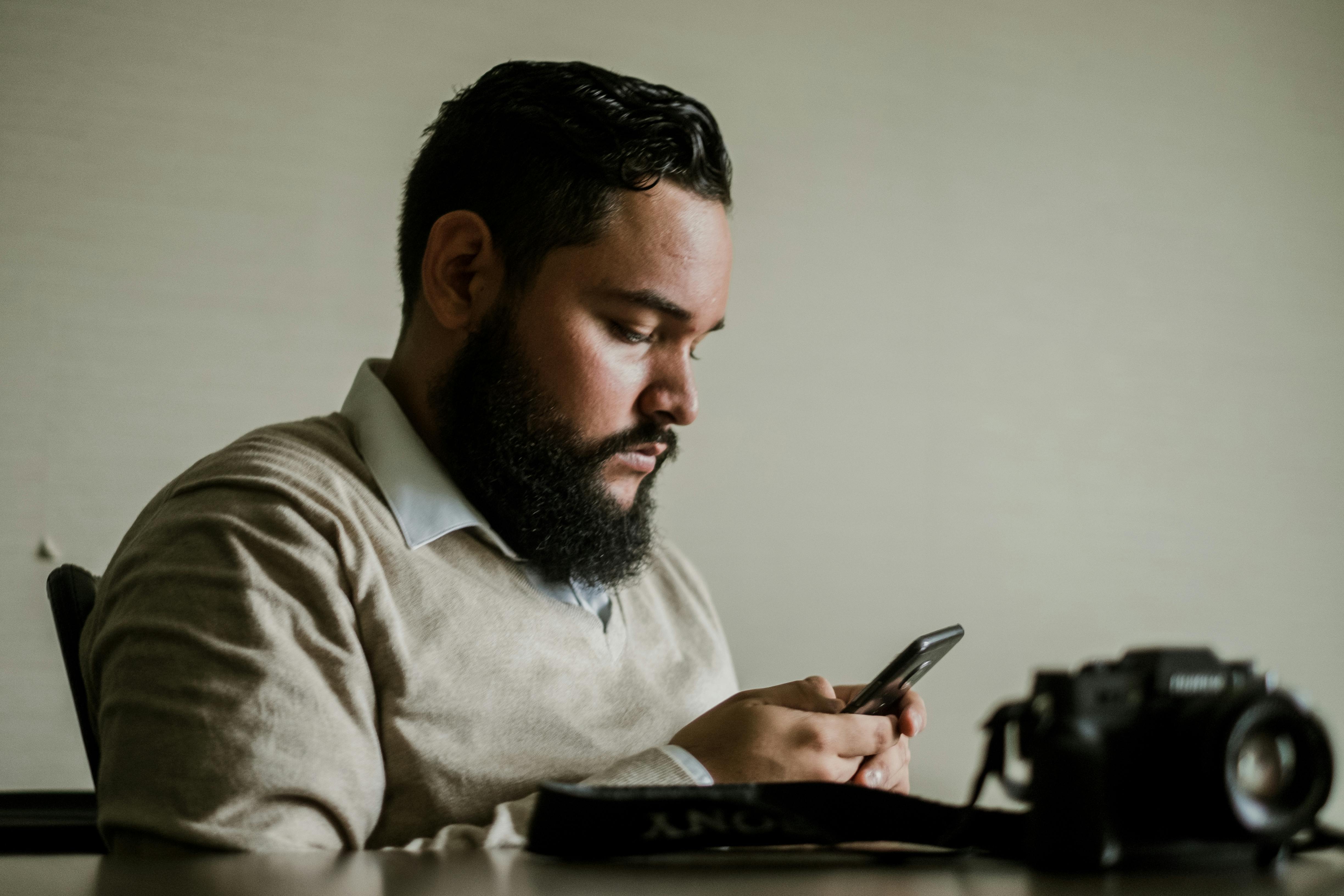 Man With Facial Hair Holds Smartphone \u00b7 Free Stock Photo