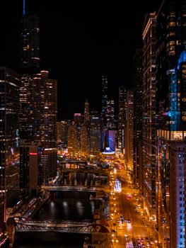 Illuminated cityscape of downtown Chicago at night, highlighting the river and iconic skyscrapers.