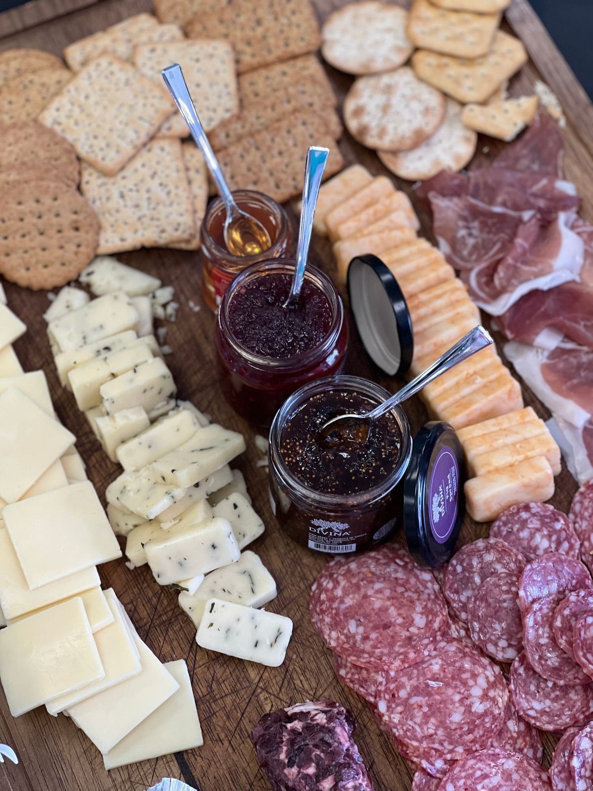 Grazing board with cheeses, cured meats, crackers and jam on rustic wood for a New Year's Eve party at home