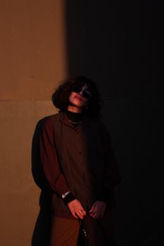 Stylish woman posing in dramatic shadow and light contrast outdoors.