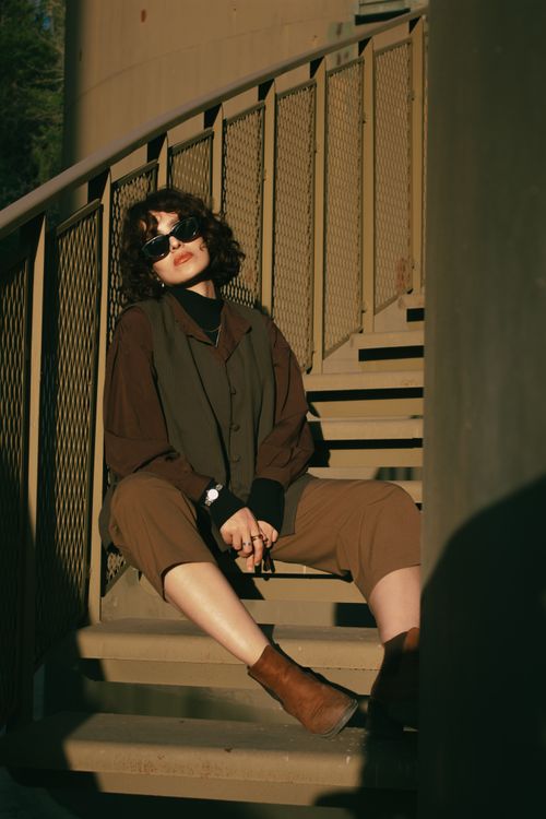 Free A fashionable woman in sunglasses sits on a metal staircase enjoying a sunny day. Stock Photo