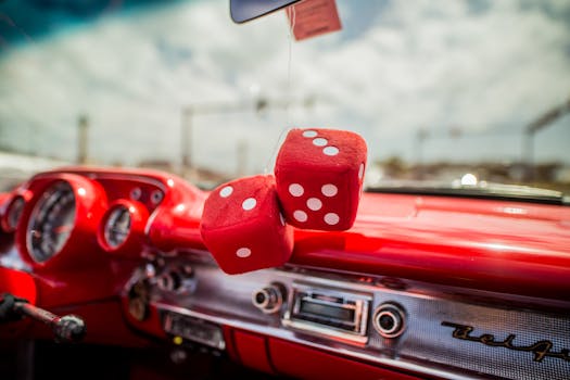 Close-up of a classic car interior with red dice hanging from the mirror, showcasing retro style.