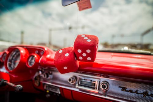 Free Close-up of a classic car interior with red dice hanging from the mirror, showcasing retro style. Stock Photo