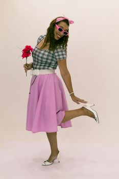 Stylish woman in vintage outfit holding flowers, striking a playful pose.