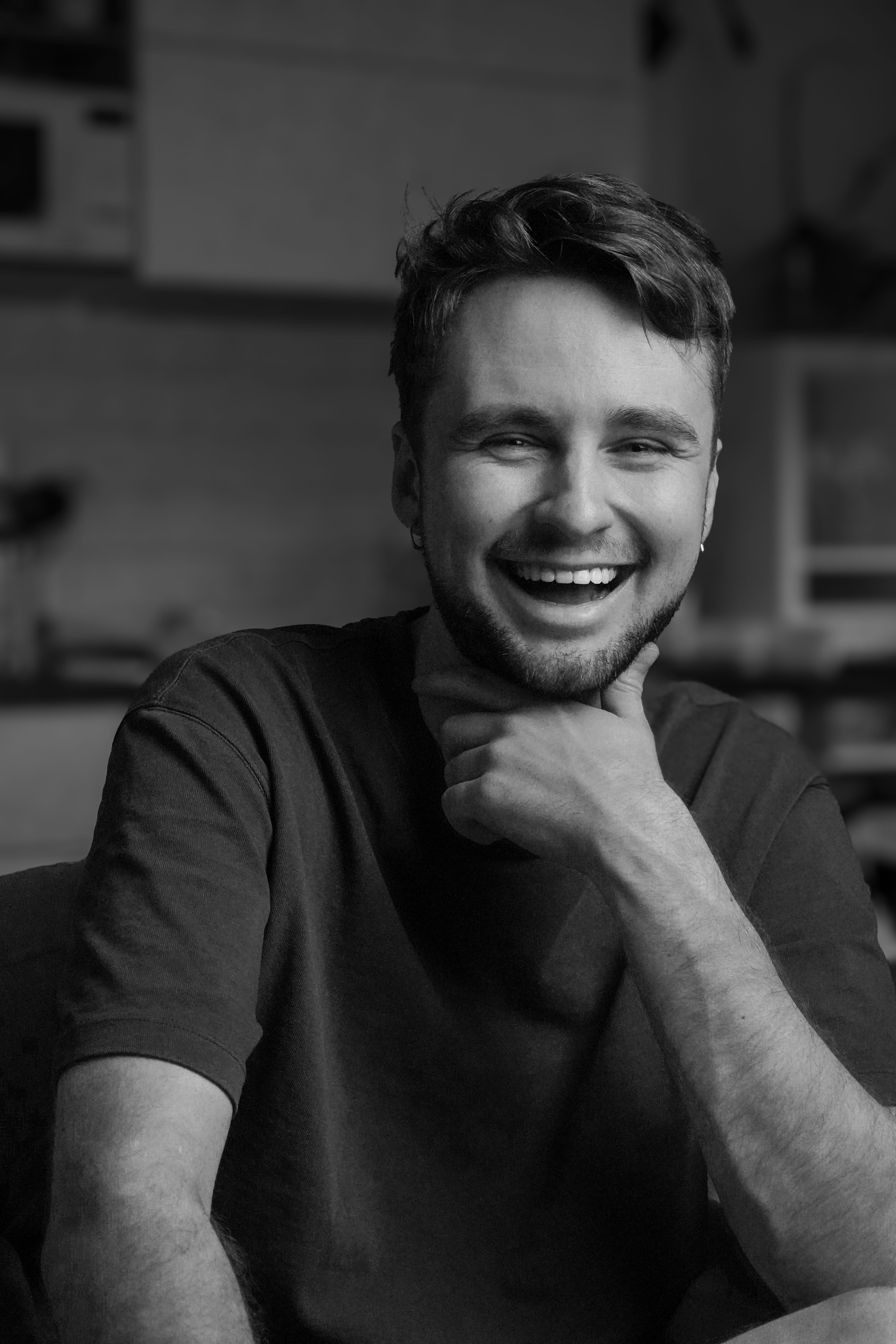 A candid black and white portrait capturing a happy young man with a cheerful expression in a relaxed setting.
