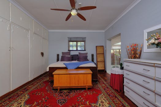 Elegant bedroom featuring modern decor, wooden furniture, and vibrant carpet accenting.