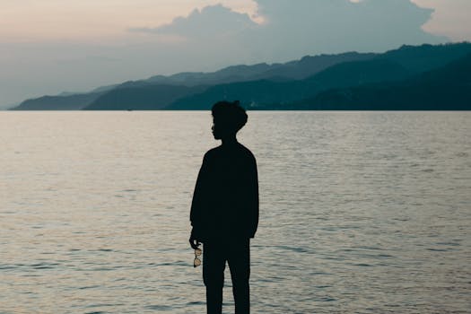 Tranquil scene of a person silhouetted against the calm ocean waters at dusk in Gorontalo, Indonesia.