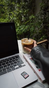 Stylish outdoor cafe setting in Bursa with a laptop, iced coffee, and greenery, capturing a tranquil spring vibe.