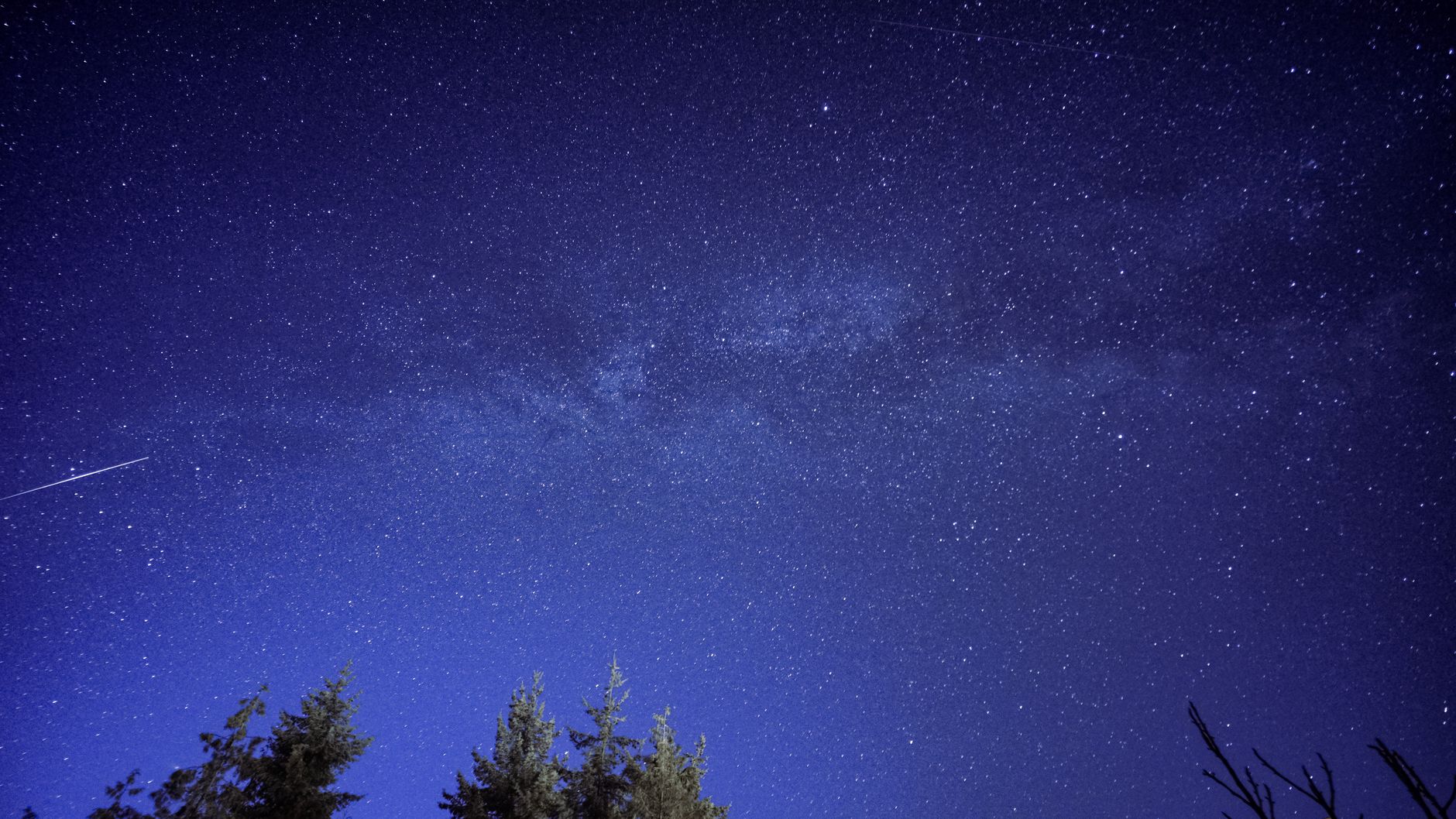 Gece gökyüzünde parlak bir kuyruklu yıldızın geçişini ve atmosfere giren meteorların oluşturduğu ışık izlerini gösteren etkileyici uzay manzarası.