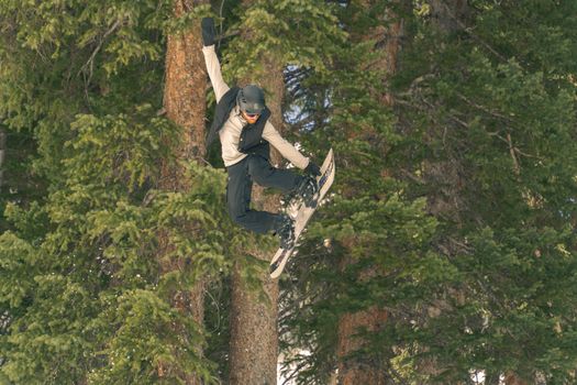 Snowboarder catching air in Brighton, Utah with evergreen backdrop.