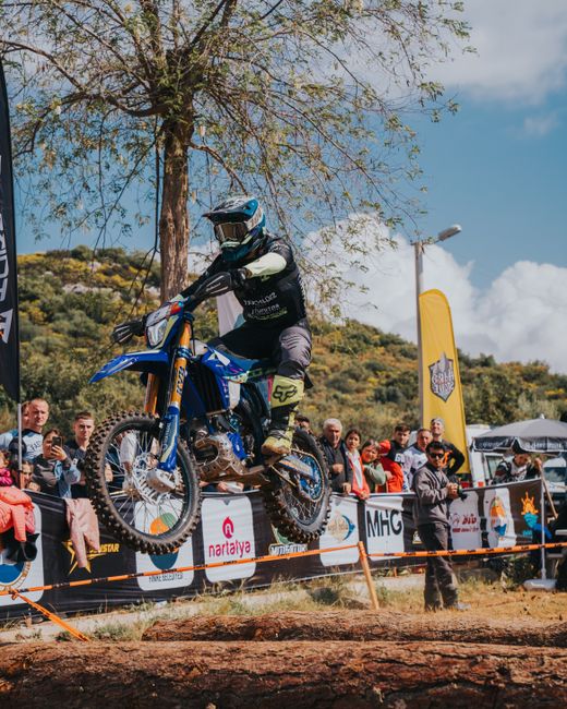A rider performs a high jump on an enduro motorbike during a competitive outdoor race.