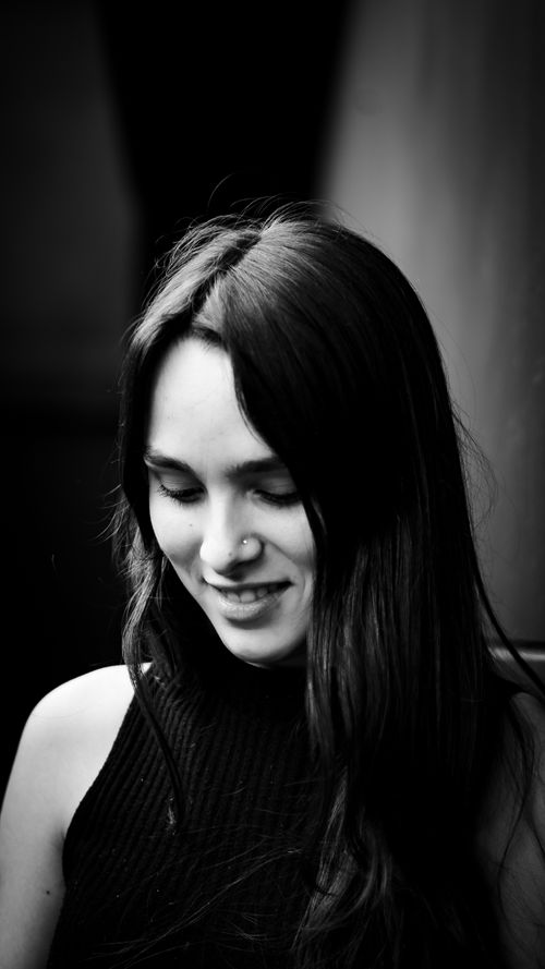 Free Close-up black and white portrait of a young woman looking down with a smile. Stock Photo