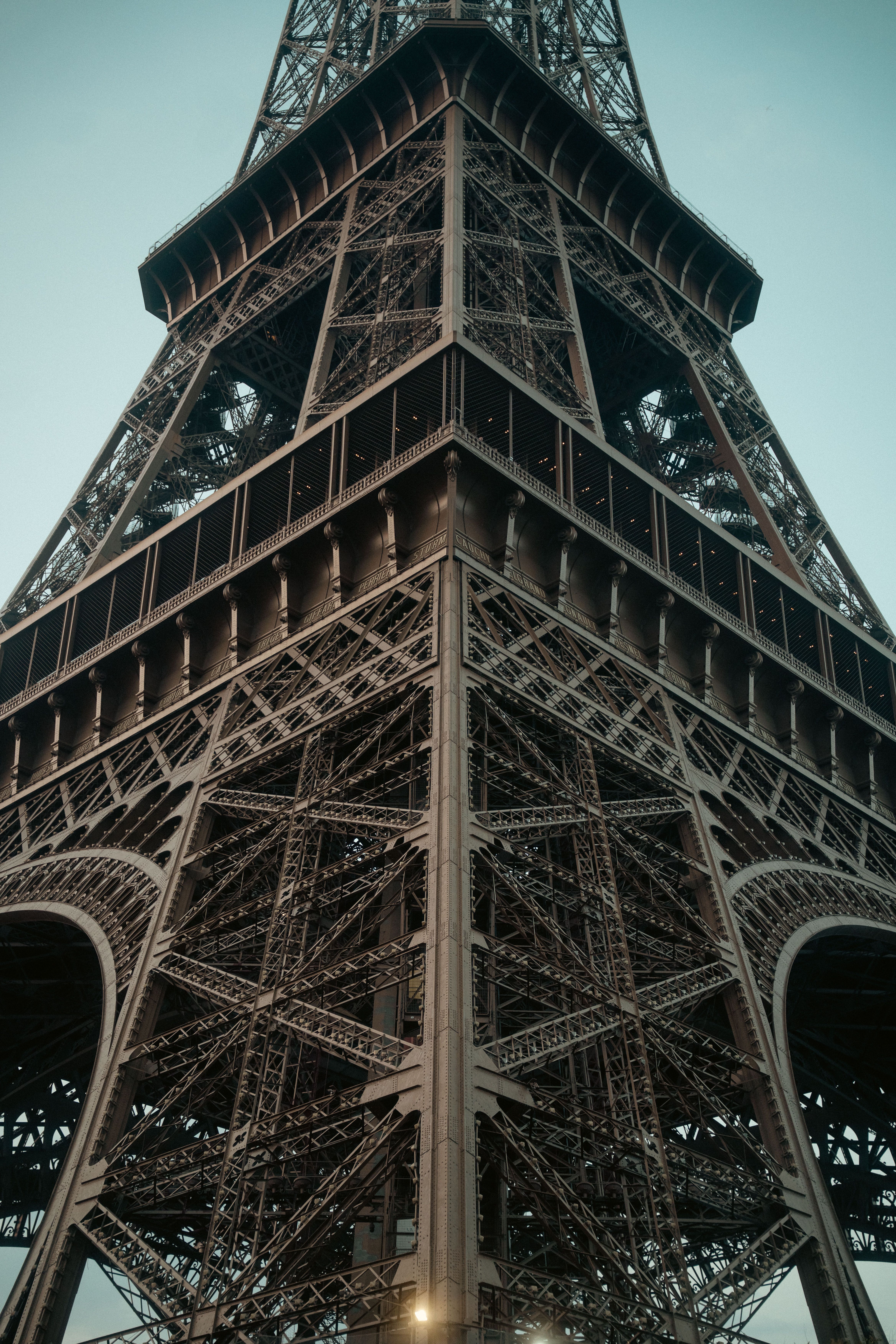 Dramatic upward view of the Eiffel Tower's metal structure in Paris, France.