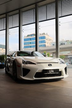 Elegant white Lexus LFA parked inside a contemporary showroom with urban backdrop.