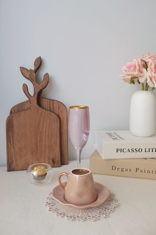 Free A stylish arrangement of a ceramic cup, pink flowers, and art books on a table. Stock Photo