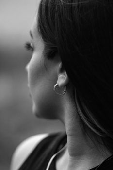 A black and white portrait of a woman with hoop earrings, looking away thoughtfully.