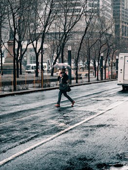 Person with umbrella crossing wet street in downtown Montreal on a rainy day.