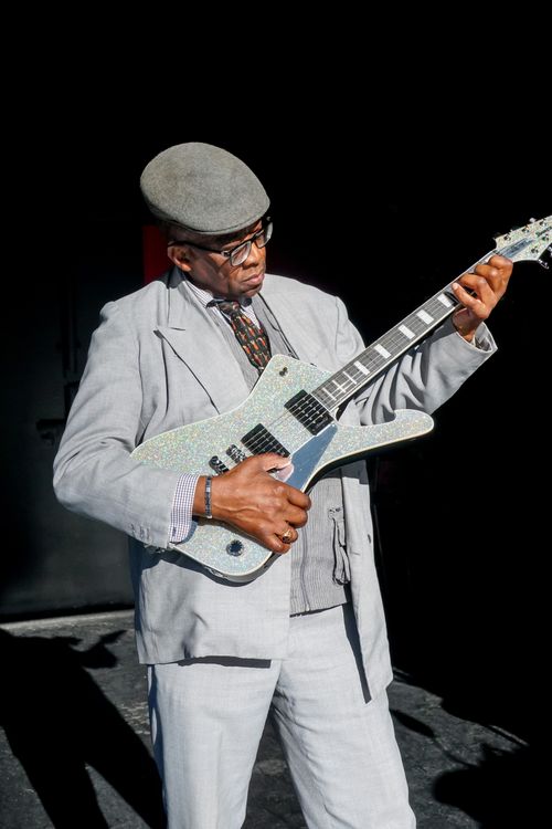 Free Senior man in stylish attire playing electric guitar outdoors under sunlight. Stock Photo