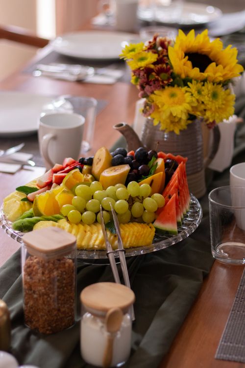 Free Bright fruit arrangement on dining table with a sunflower bouquet, perfect for brunch settings. Stock Photo
