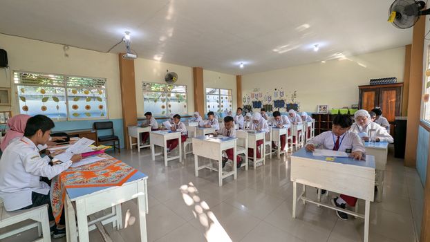 Students in an Indonesian classroom taking an exam under natural lighting. 31940733