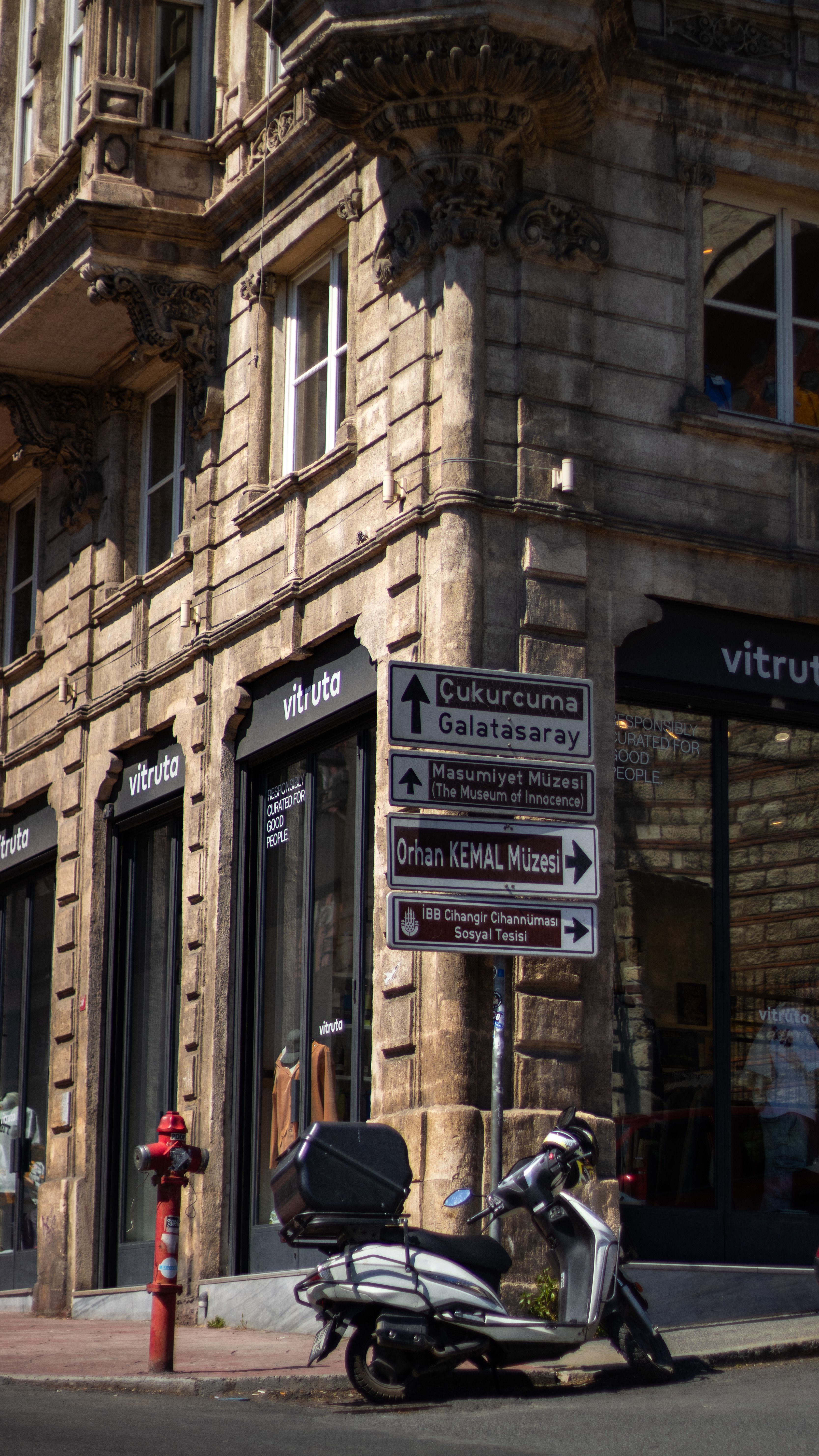 A corner view of a historic building in Istanbul showcasing street signs and a parked scooter.