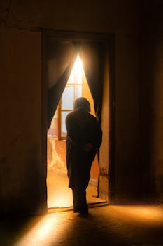 A lonely silhouette standing in a sunlit doorway of an old building in Istanbul, Türkiye.