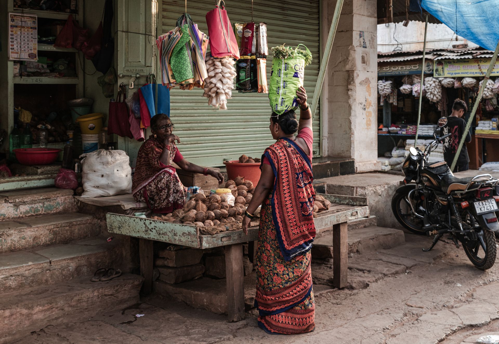 Authentic Indian market stall with women in traditional attire interacting. Vibrant cultural snapshot.