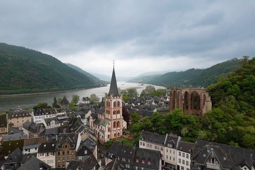 Free Picturesque village scene with church and ruins beside the Rhine River. Stock Photo