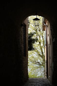 View through an old stone archway revealing lush trees in San Leo, Italy.