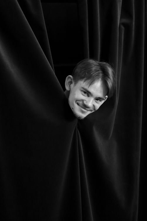 Free Black and white photo of a person humorously peeking through velvet curtains. Stock Photo