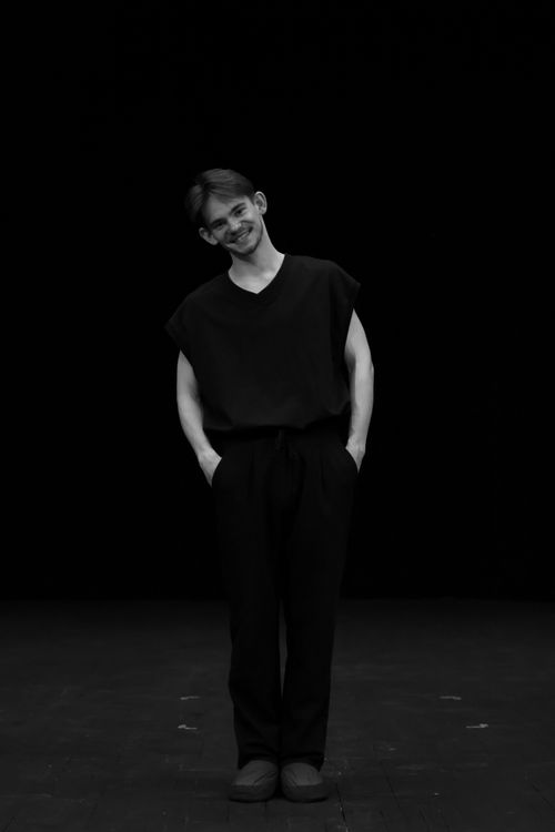 Free Artistic black and white portrait of a person standing, smiling against a dark background. Stock Photo
