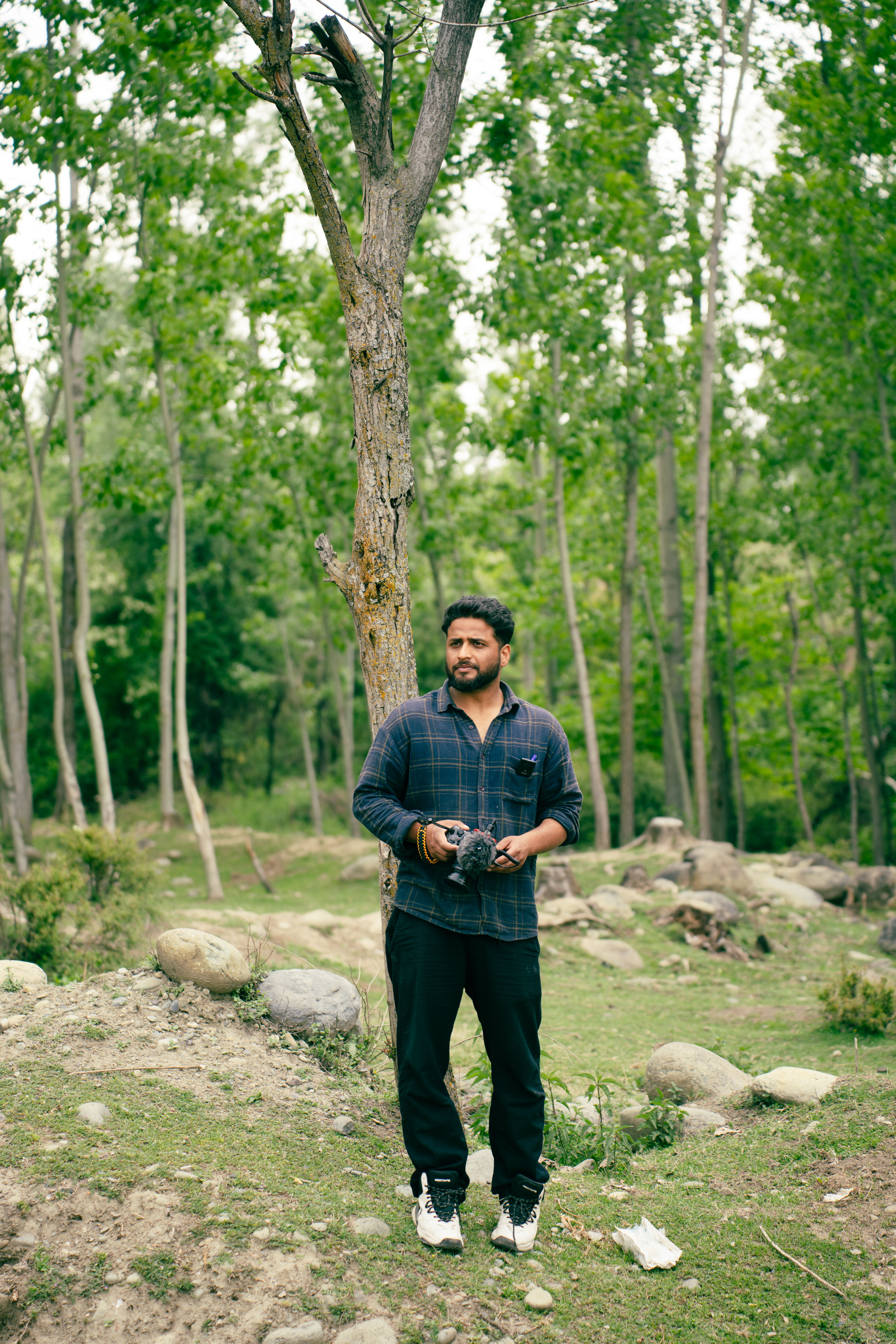 A man stands in a lush forest of Badgam, Kashmir, capturing the natural beauty.