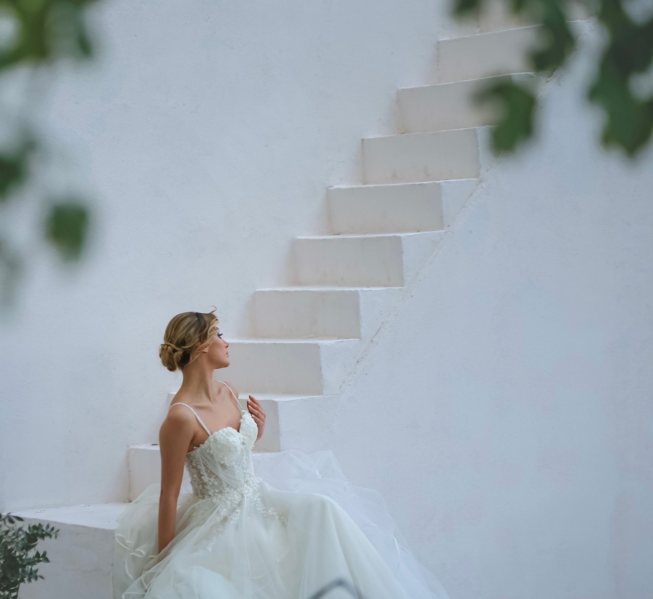 A bride in an elegant white dress poses by a minimalist staircase outdoors. - Photo by Focus  Weddingg on Pexels