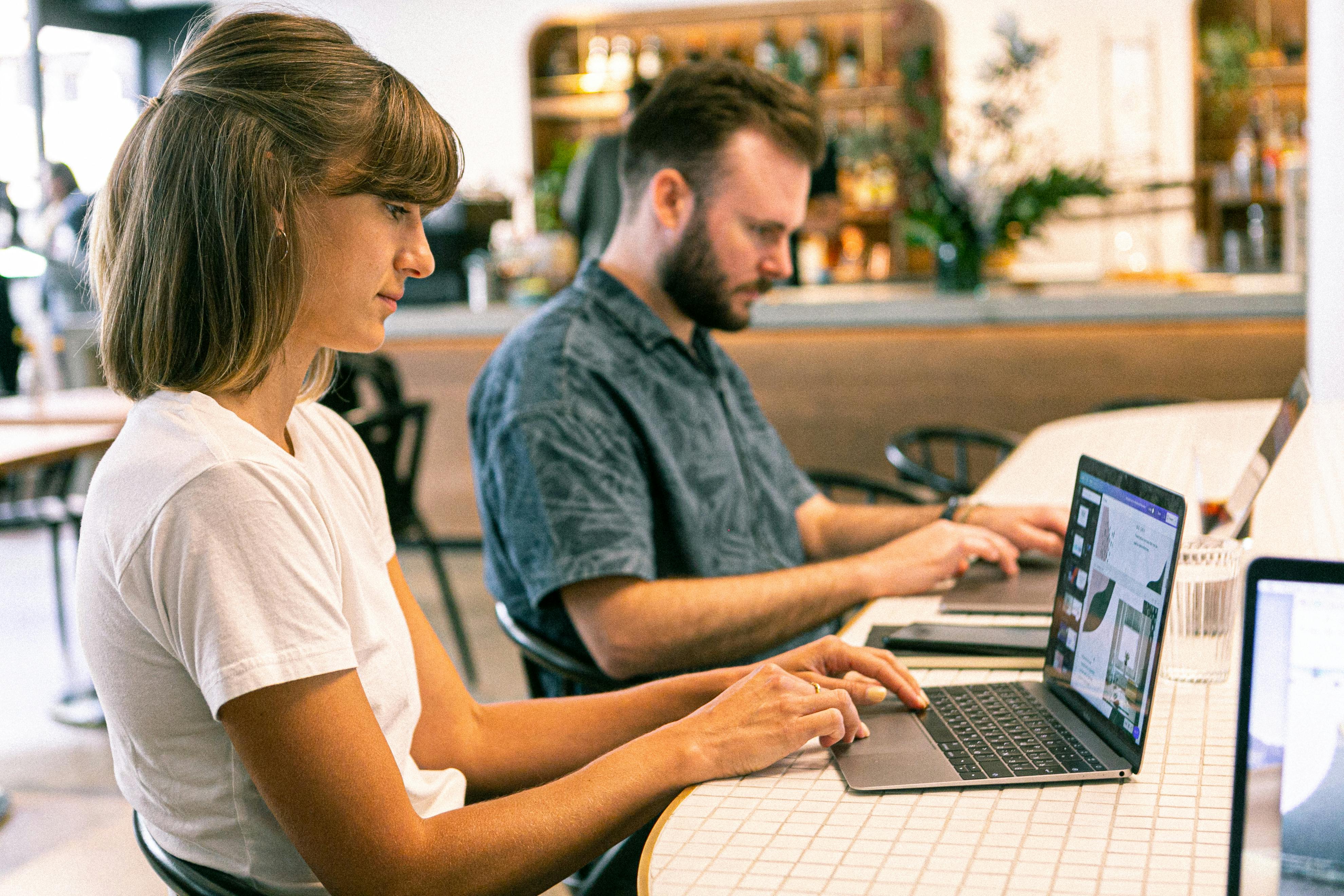 a woman in a white shirt typing on her laptop.