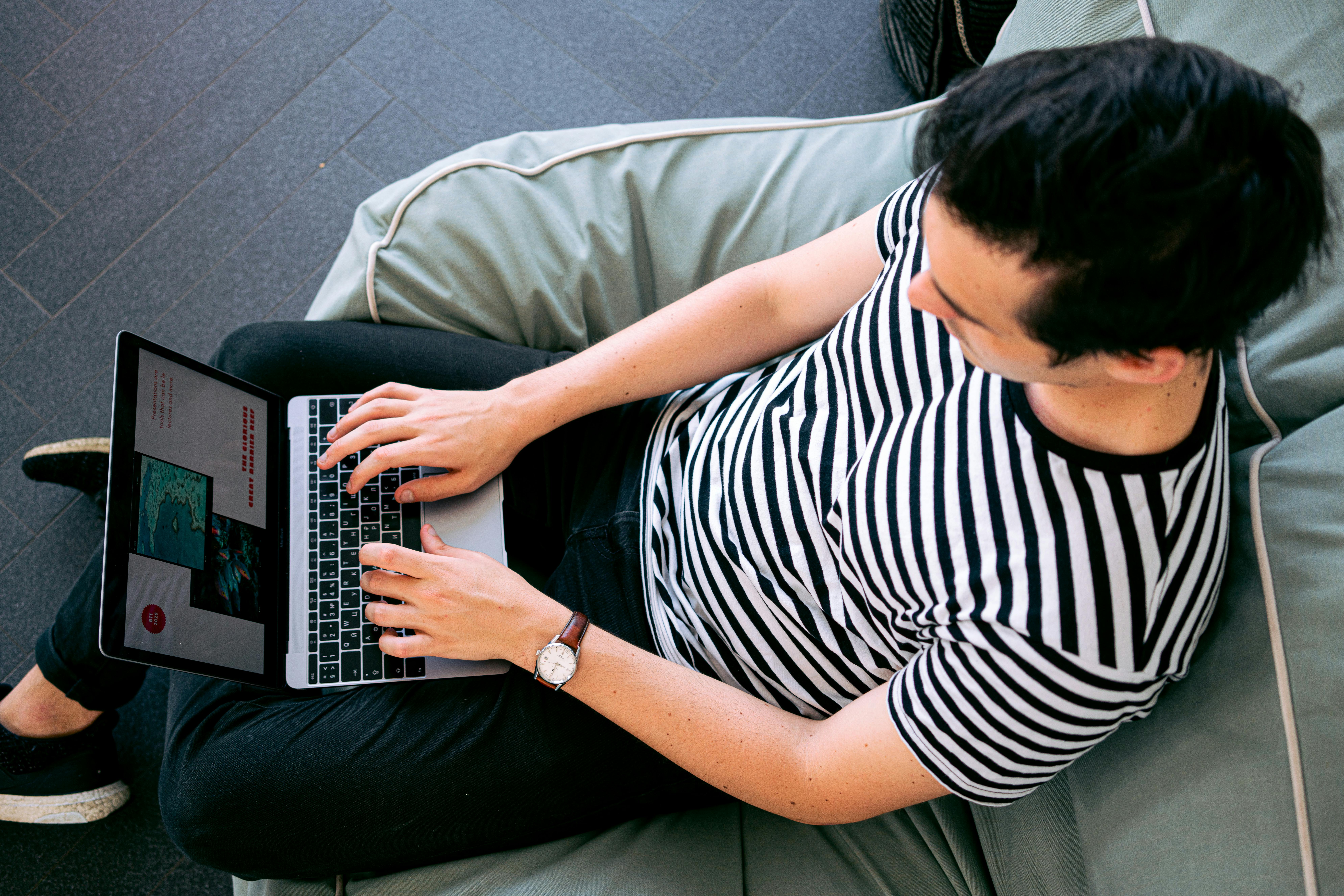 a man in a striped shirt typing on his computer.