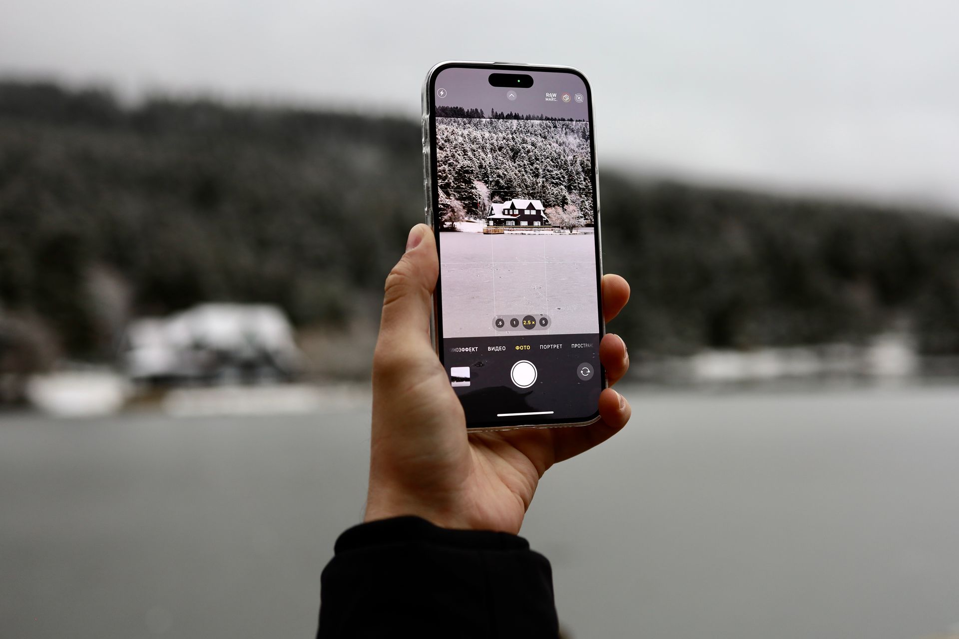 A person capturing a snow-covered house and landscape in Bolu, Turkey with a smartphone.