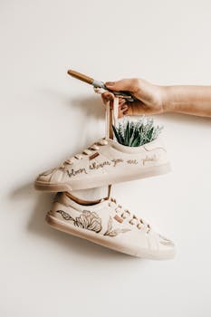 手持装饰鞋，上面有植物刺绣和创意引用设计