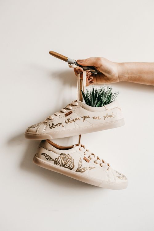 Free Hand holding decorated shoes with plant embroidery and creative quote design. Stock Photo