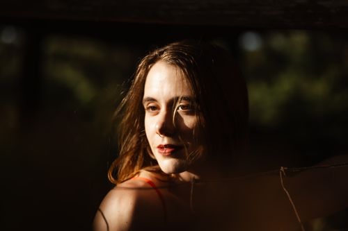 Free A woman in warm lighting during a sunset, creating a serene mood. Stock Photo