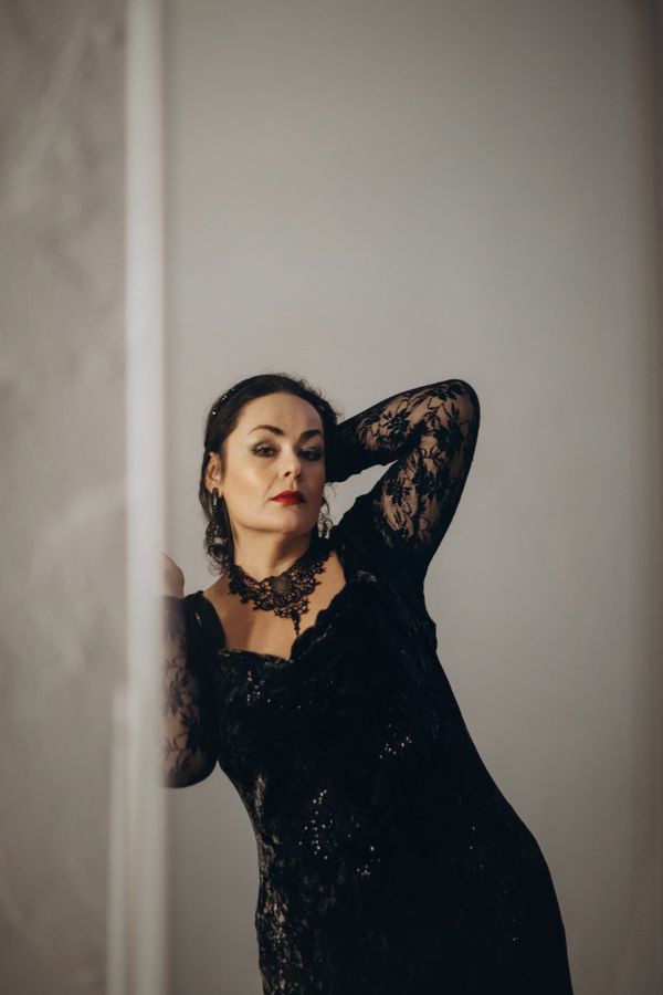 Elegant woman in a black dress leaning against a wall