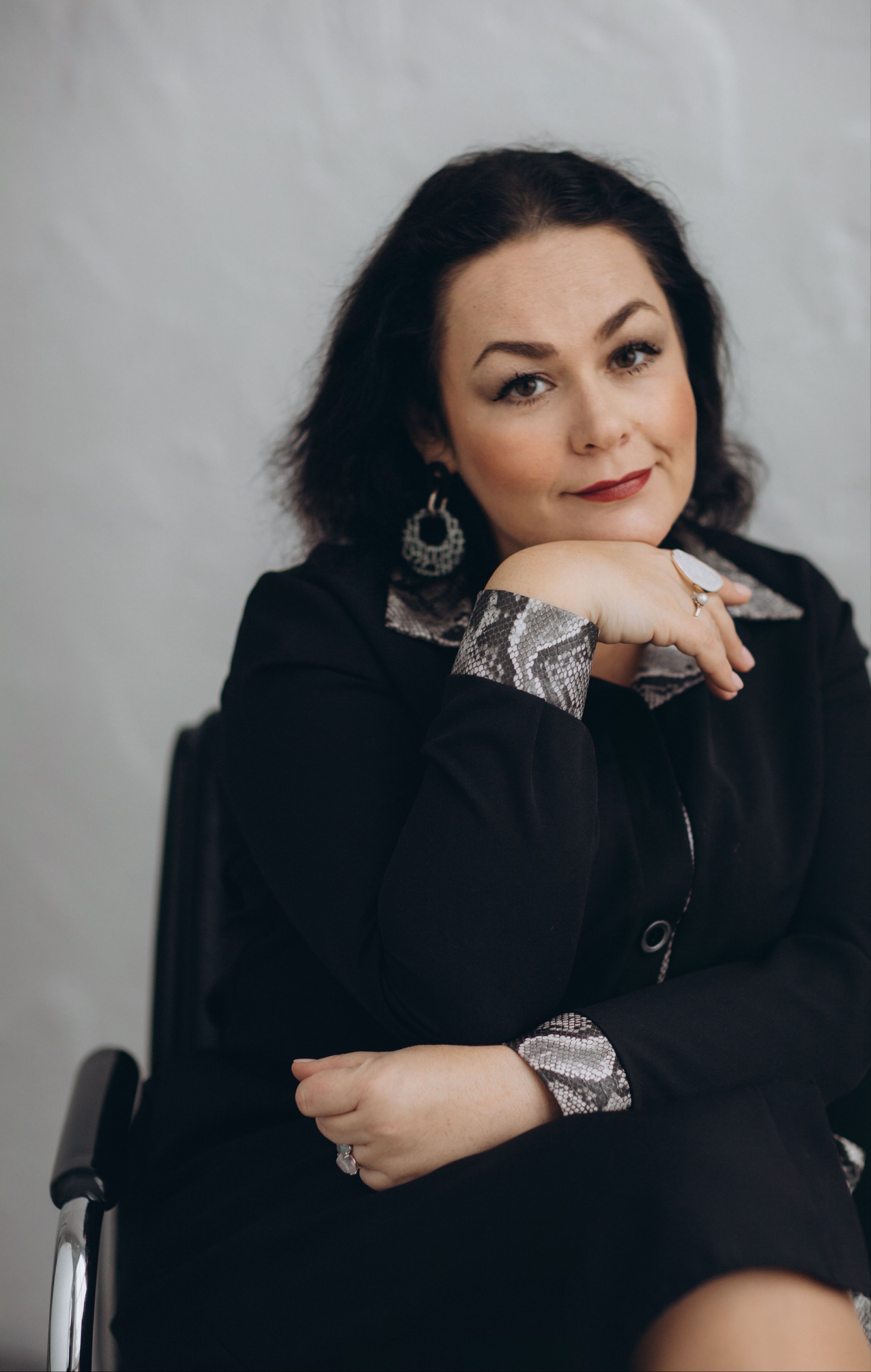 Portrait of an elegant woman in a black outfit with thoughtful expression indoors.