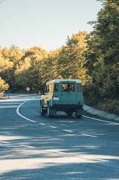 A green SUV drives through a scenic forest road, embodying adventure and exploration.