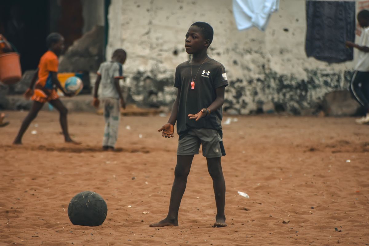 Children playing football on a sandy street