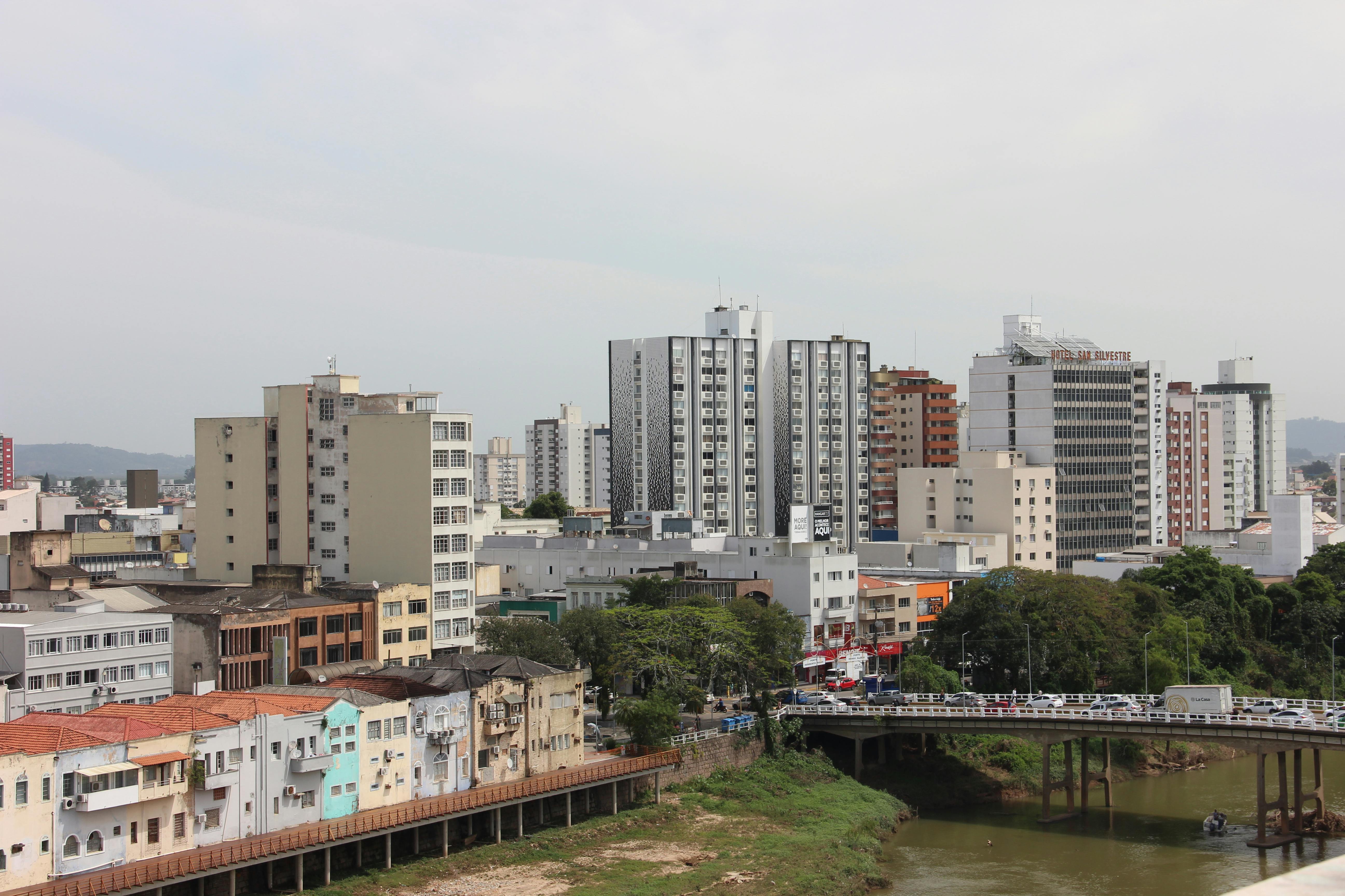A bustling cityscape with high-rise buildings and a riverside bridge, showcasing urban life.