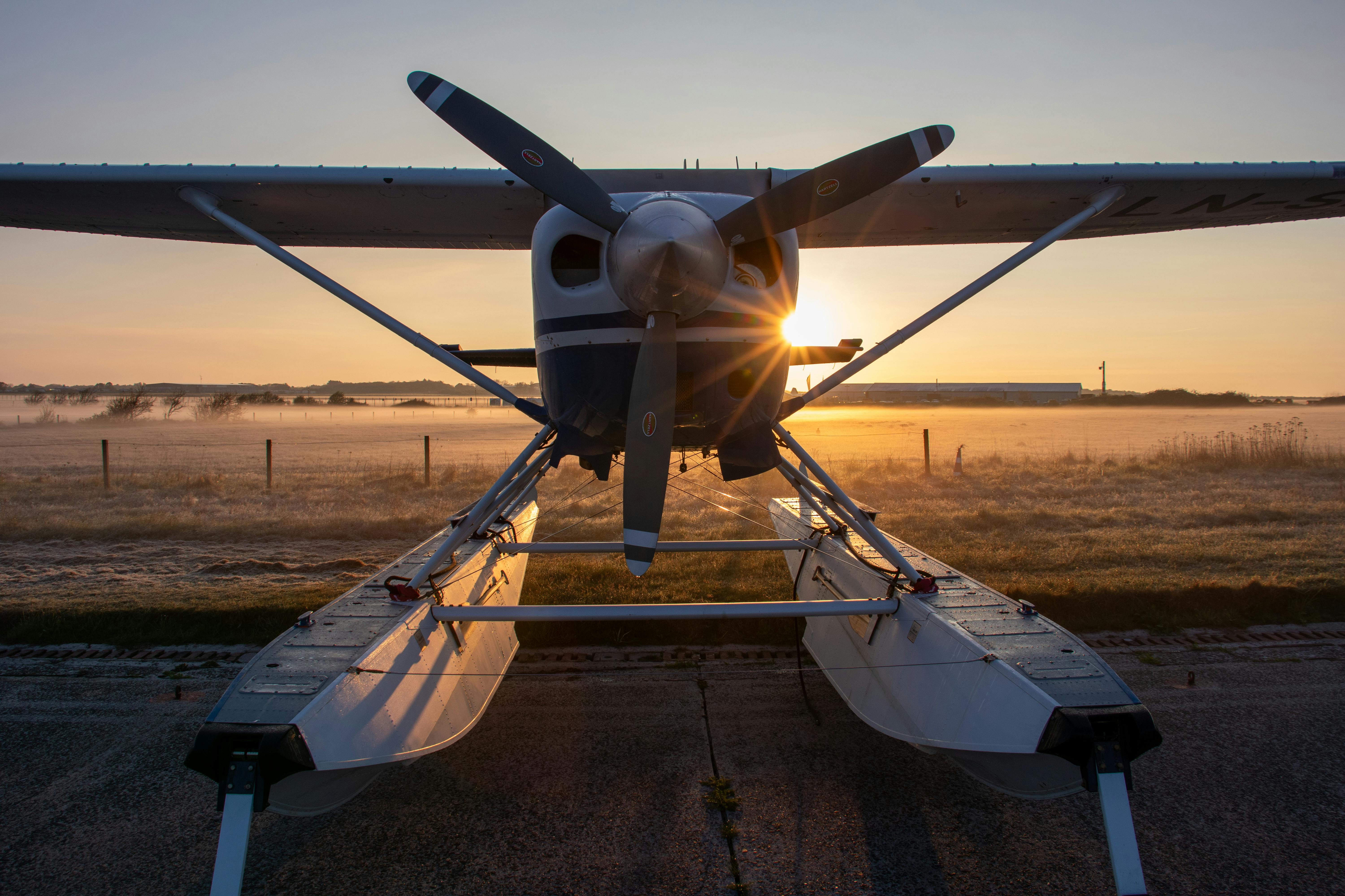 Free Seaplane with sunrise in the background casting warm morning light on a foggy airstrip. Stock Photo