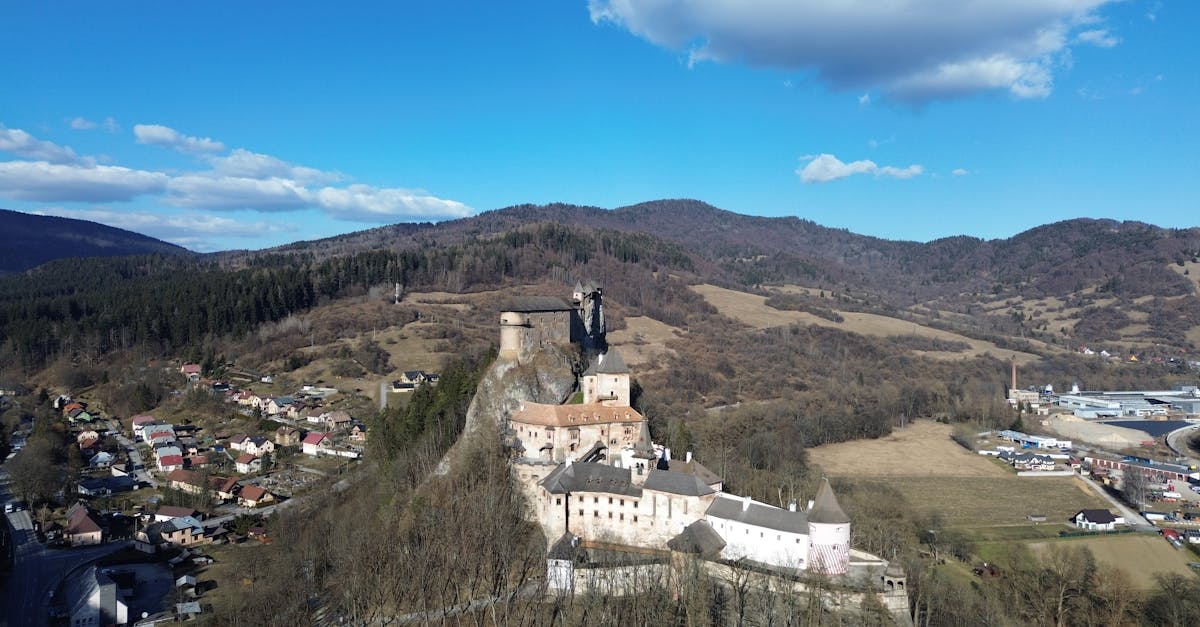 Stunning aerial view of Orava Castle surrounded by hills and a small village in Slovakia.