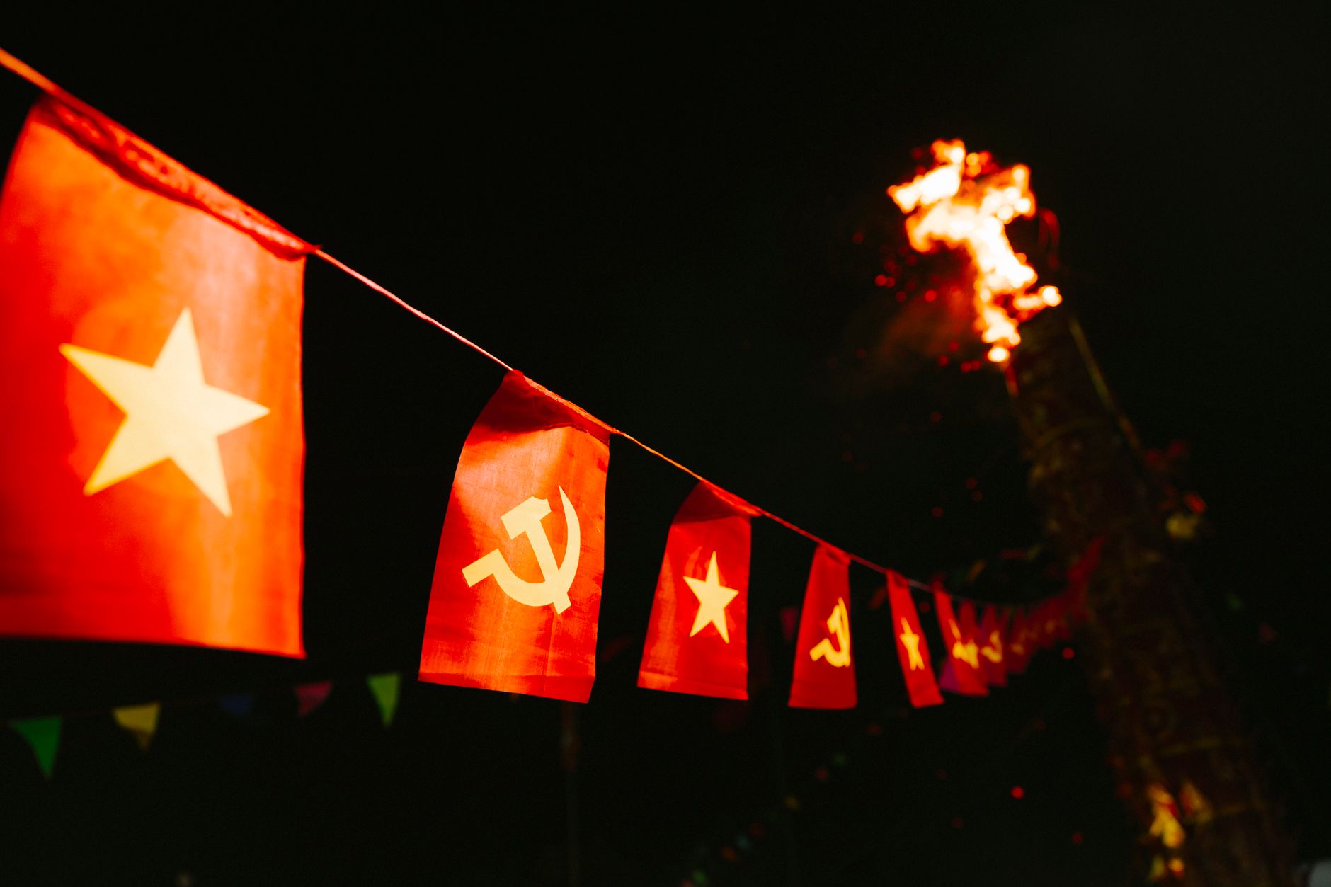 Red flags with stars and sickle hammer, large bonfire in nighttime festival.