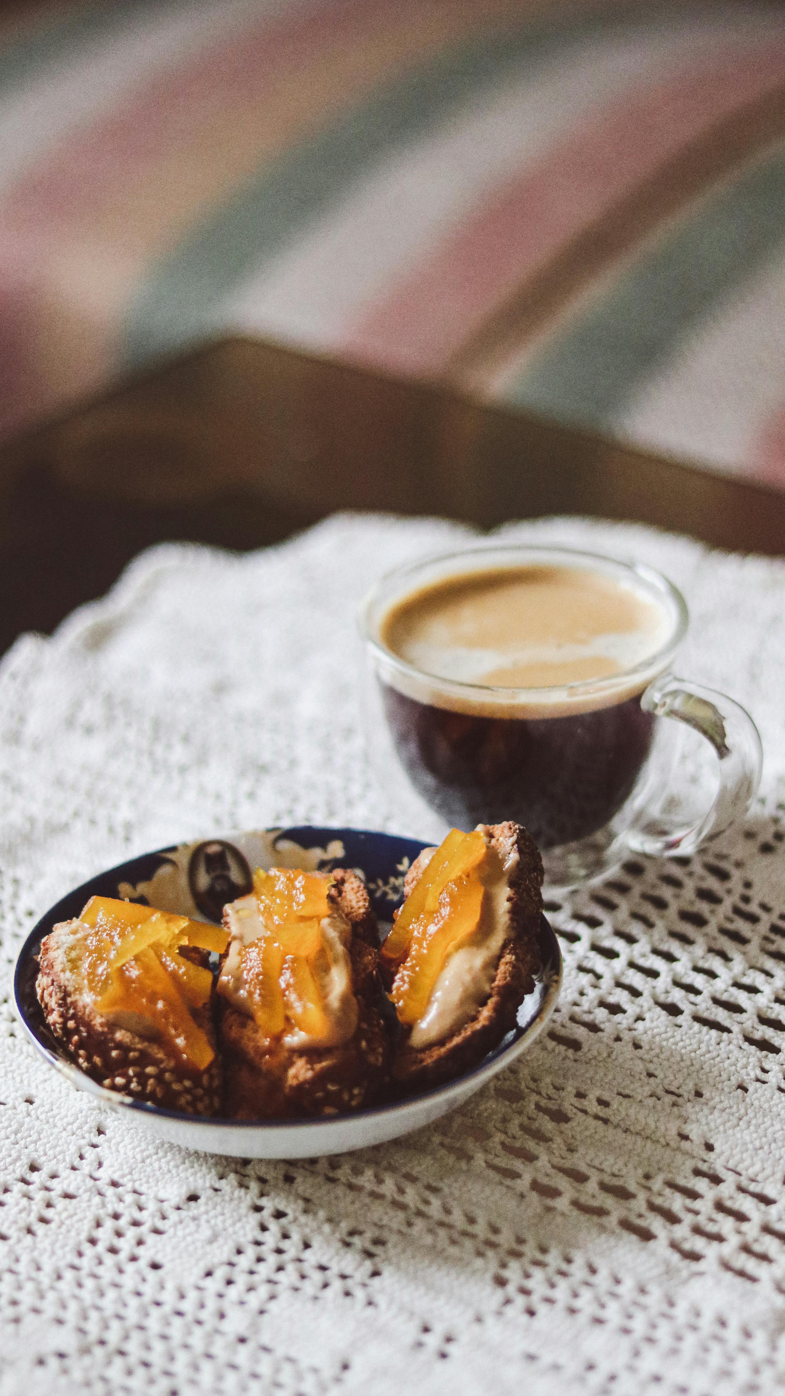 Cozy setting with a glass of espresso coffee and delicious pastries on a lace tablecloth.