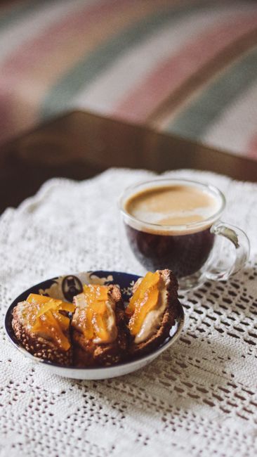 Cozy setting with a glass of espresso coffee and delicious pastries on a lace tablecloth.